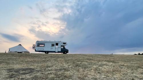 un camping-car garé dans un champ avec une tente dans l'établissement Surfer Mammut, à Ipswich