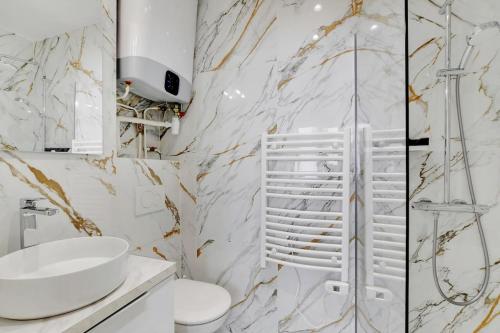 une salle de bain blanche avec un lavabo et une douche dans l'établissement Cosy au Parc des Buttes Chaumont, à Paris