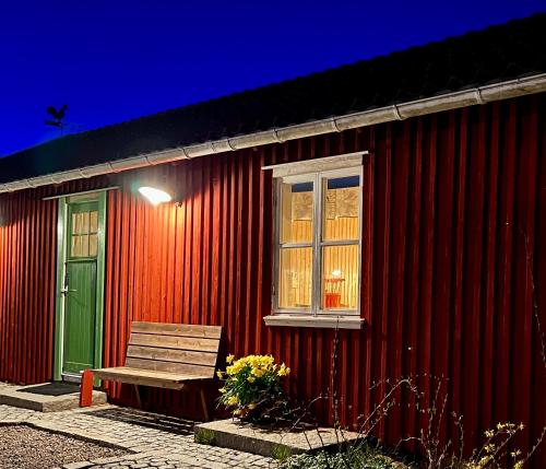 a bench sitting outside of a red building with a green door at Fiskebäckgårds gästhus in Lysekil