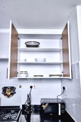 a kitchen with white cabinets and a stove top oven at The O Apartment in Ongata Rongai 