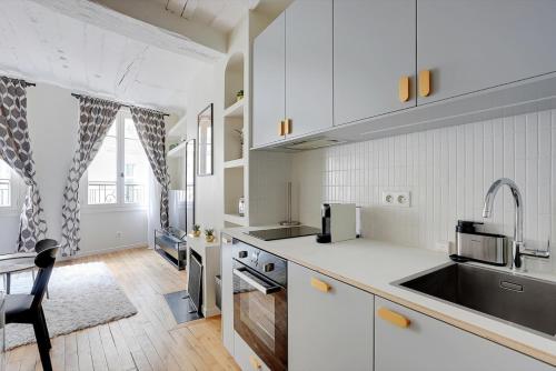a white kitchen with a sink and a stove at Saint-Honore - Sublime appartement in Paris