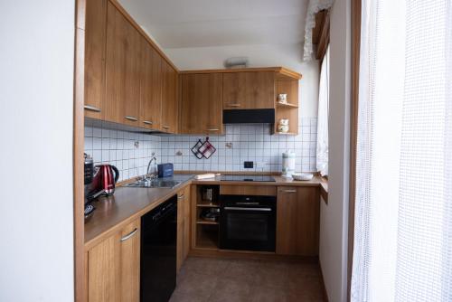 a kitchen with wooden cabinets and a black dishwasher at Pelmo Mountain Lodge con bagno turco in Borca di Cadore