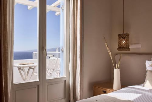 a bedroom with a door leading to a balcony at Vencia Boutique Hotel in Mýkonos City
