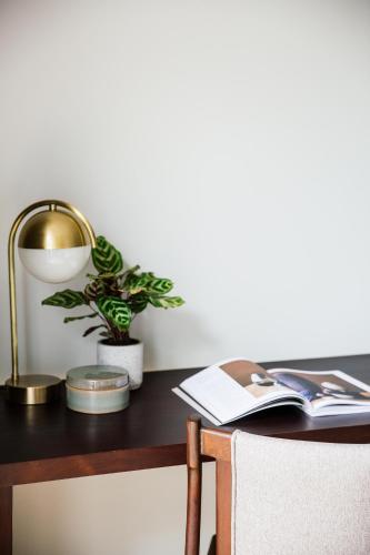 a desk with a lamp and a book and a plant at Treeline Urban Resort in Siem Reap