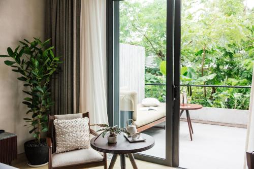 a living room with a sliding glass door with a couch at Treeline Urban Resort in Siem Reap