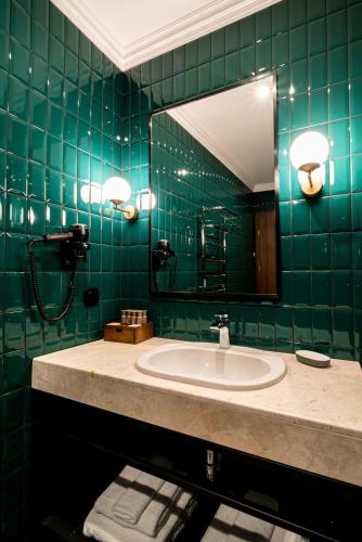 a green tiled bathroom with a sink and a mirror at Hotel Erdeli by Derenivska Kupil in Nyzhne Solotvyno