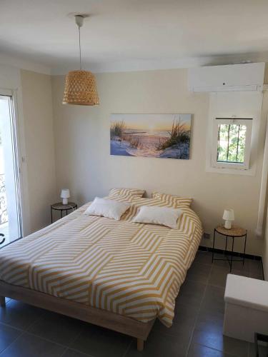 - une chambre avec un grand lit et une couverture rayée dans l'établissement Nouveau Appartement PEROLS rénové en 2024, à Pérols