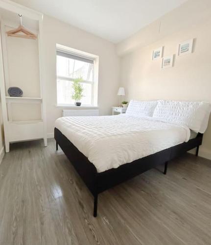 a bedroom with a large bed with white sheets and a window at Wellington Road Apartment 4 in Southtown
