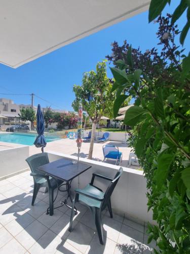 a patio with a table and chairs and a pool at Leonidas Studios & Apartments in Georgioupolis