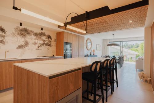 een keuken met een groot eiland met barkrukken bij Villa Cordouan avec piscine en bord de mer in Royan