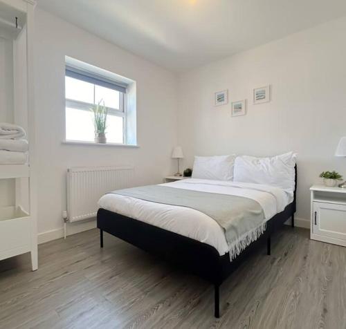 a white bedroom with a large bed with a window at Wellington Road Apartment 5 in Southtown