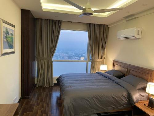 a bedroom with a bed with a ceiling fan and a window at 2 Bed Room Suite-Elysium Tower Opp Centaurus Mall Islamabad in Islamabad