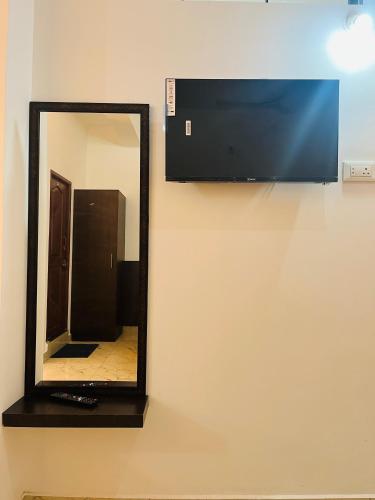 a mirror hanging on a wall with a television at Nagashree stay inn in Chikmagalūr