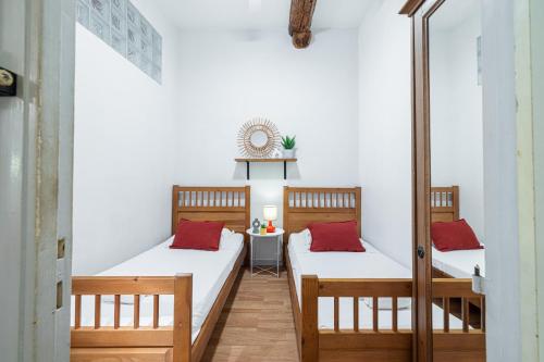 deux lits dans une chambre avec des murs blancs et des oreillers rouges dans l'établissement 2 Bdr with Independent Studio - Old Town, à Nice