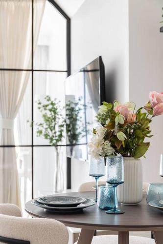 a dining room table with a vase of flowers on it at Studio apartment MeDoRe Tower in Dubai