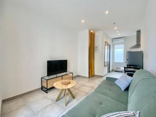 un salon avec un canapé vert et une télévision dans l'établissement SweetHome Sully, à Nîmes