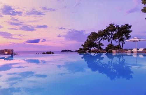 a pool with blue water and an island in the distance at Sani Club in Sani Beach
