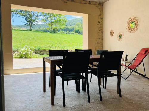 ein Esszimmer mit Tisch und Stühlen und einem Fenster in der Unterkunft La Ferme de Bournat in La Répara