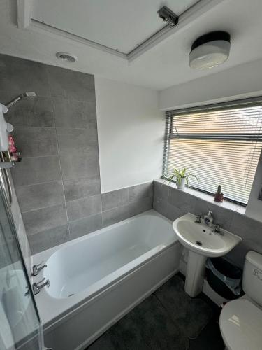 a bathroom with a tub and a sink and a toilet at 3 bedroom guest House in Brierley hill Contractors & Families Welcome DY5 in Woodside