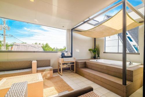 une salle de bain avec baignoire et une grande fenêtre dans l'établissement Urban Resort Villa ILILANI, à Inbu