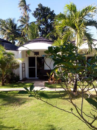 a white house with palm trees in the yard at White Chocolate Hills Resort in Zamboanguita