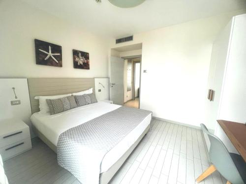 a white bedroom with a large white bed in it at Hotel & Residence Cavalluccio Marino in Rimini