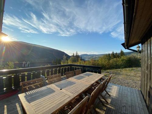 a wooden table and chairs on a deck with a view at Hafjell Grenda lejligheder og hytter in Hafjell