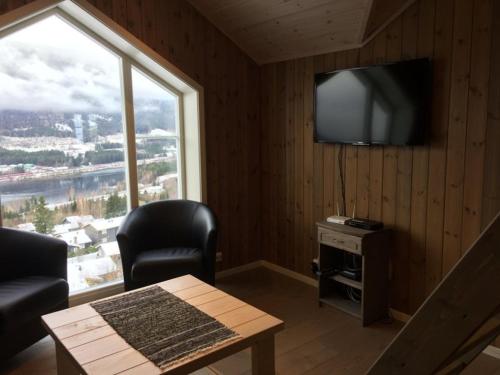 a living room with a large window and a television at Hafjell Grenda lejligheder og hytter in Hafjell