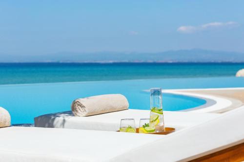 a table with a bottle of wine next to a pool at Sani Beach in Sani Beach