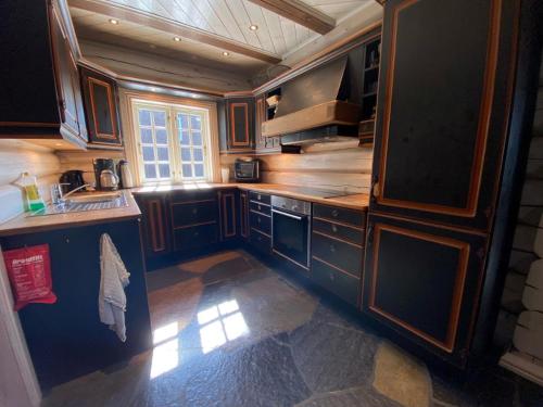 a large kitchen with wooden cabinets and a window at Hafjell Grenda lejligheder og hytter in Hafjell