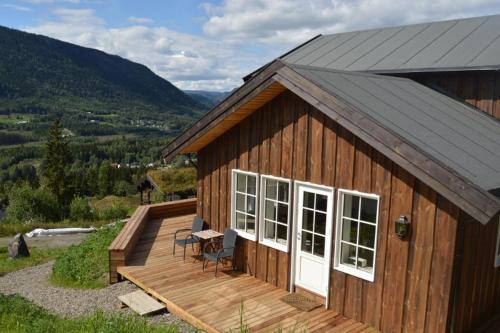 a building with a deck with a table and chairs at Hafjell Grenda lejligheder og hytter in Hafjell