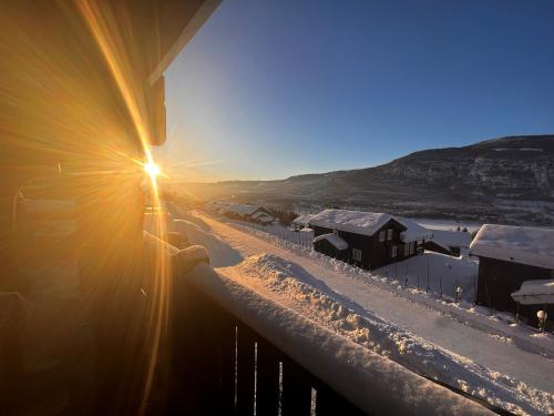 a sun shining on a balcony with snow on the ground at Hafjell Grenda lejligheder og hytter in Hafjell