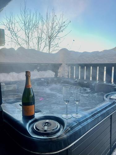 a bottle of champagne and two glasses in a hot tub at Hafjell Grenda lejligheder og hytter in Hafjell