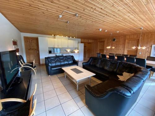 a living room with black leather furniture and a table at Hafjell Grenda lejligheder og hytter in Hafjell
