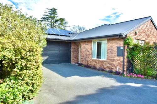 a house with a garage with solar panels on it at Sunny Garden Retreat - 3-BR Home near Mall, City & Airport in Christchurch