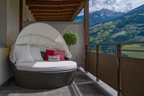 a wicker chair on a balcony with a view at Landhaus Freiburgerhof in Rifiano