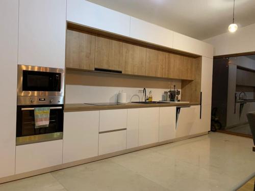 a kitchen with white cabinets and a stove and microwave at Aurorae Residence in Recaş