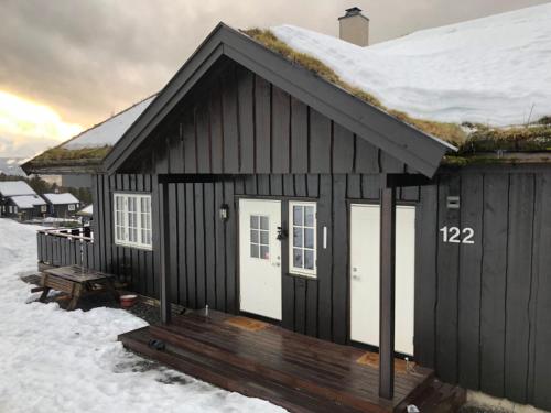 a small house with a deck in the snow at Hafjell Grenda lejligheder og hytter in Hafjell