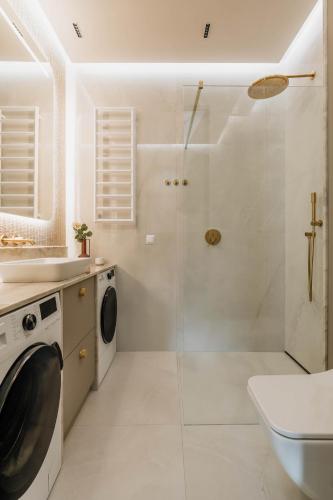 a bathroom with a shower and a washing machine at Sol Marina Resort Wyspa Sobieszewska II - LoftAffair Collection in Wiślinka