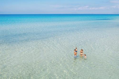 three people standing in the water in the ocean at Sani Beach in Sani Beach