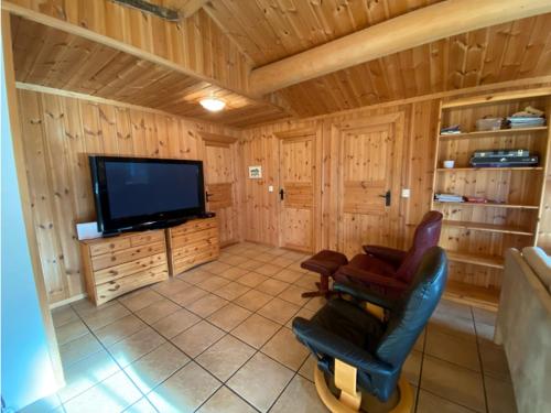 a living room with a flat screen tv and chairs at Hafjell Grenda lejligheder og hytter in Hafjell