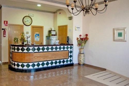 un vestíbulo con un mostrador con un reloj en la pared en Hotel Plaza Escribano en Moguer