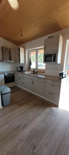 a kitchen with white cabinets and a wooden floor at Schöne Drei Zimmerwohnung in Ebersbach an der Fils