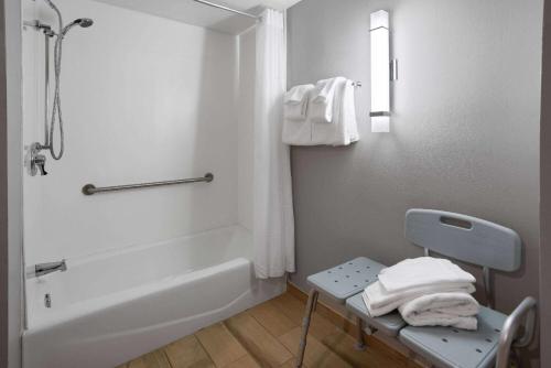 a bathroom with a shower and a chair with towels at La Quinta Inn & Suites by Wyndham Mooresville in Mooresville