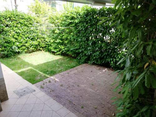 a garden with green bushes and a brick patio at residenza acquamarina fronte mare in Paestum