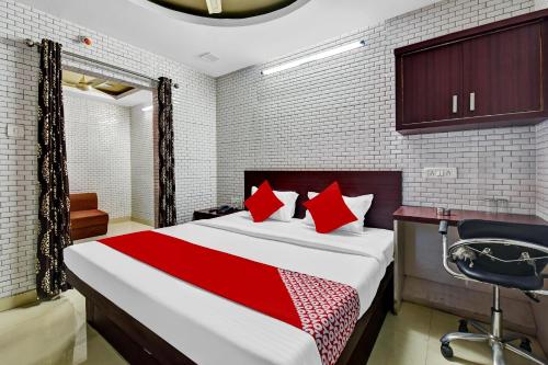 a bedroom with a bed with red pillows and a desk at Hotel O Eleven Hotel & Banquet in Kota