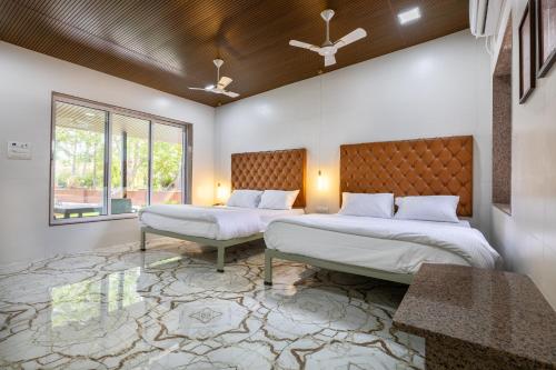 two beds in a room with two windows at Coco Bliss By Mauli Stays in Manor
