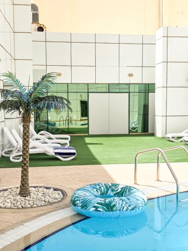 a swimming pool with a palm tree in front of a building at Stylish 1BR Apartment! Near Metro & Stroll to Dubai Marina in Dubai