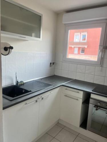 a white kitchen with a sink and a window at Appartement Les Terrasses du Port in Port-de-Bouc