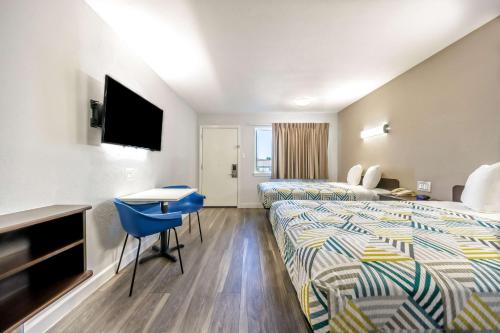a hotel room with two beds and a desk at Studio 6 Fort Worth, TX - Stockyards East in Fort Worth